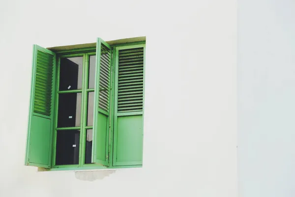 window with green shutters on white background