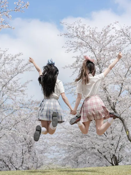 two young girls jumping in the park