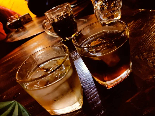 glass of whiskey with ice and salt on wooden table