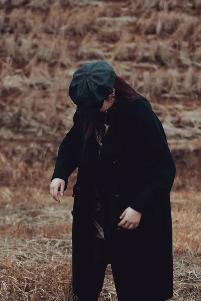 young woman in a black dress with a hood in the forest
