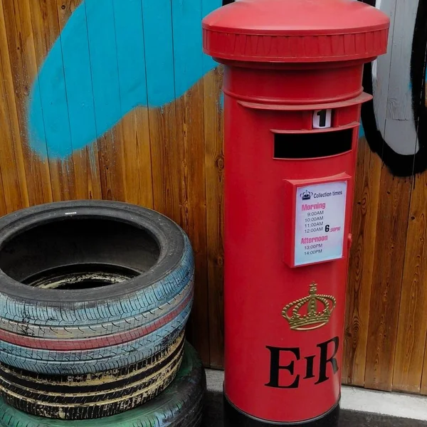 red mailbox with a lot of different sizes and a wooden box