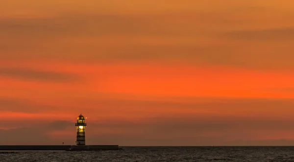 lighthouse at sunset, the sea, the sun sets, the sky and the clouds