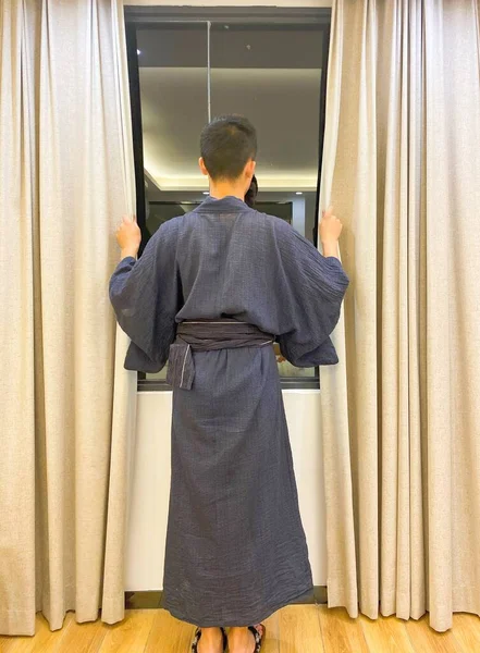 rear view of a young man with a window curtain