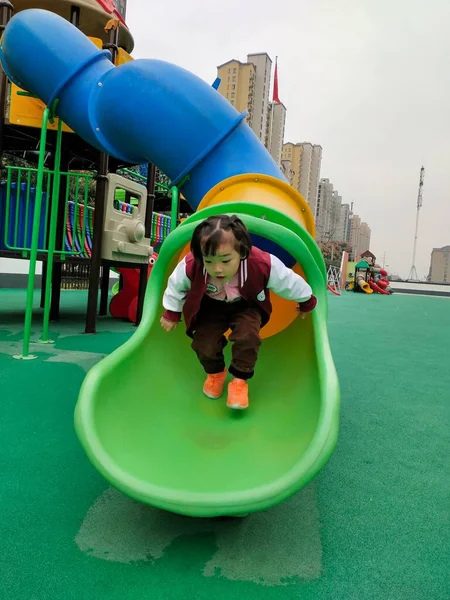 little boy playing with a slide in the park