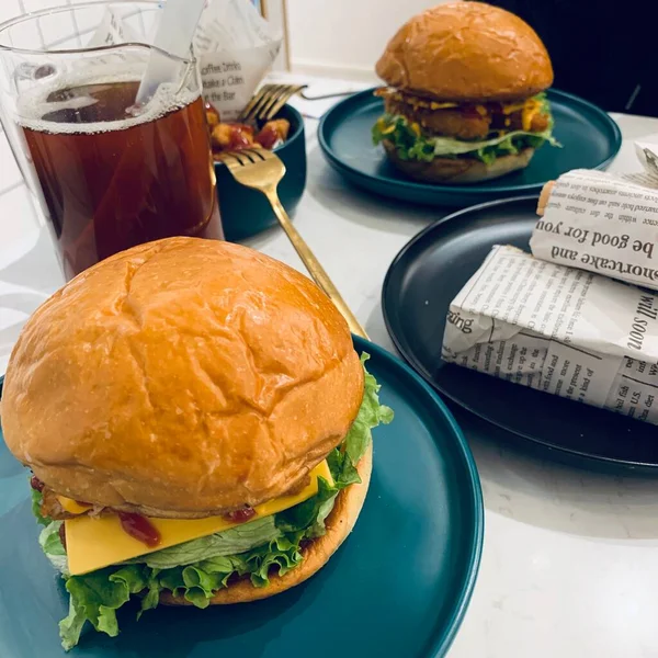 burger with chicken, cheese and tomato, lettuce and ketchup on a white plate