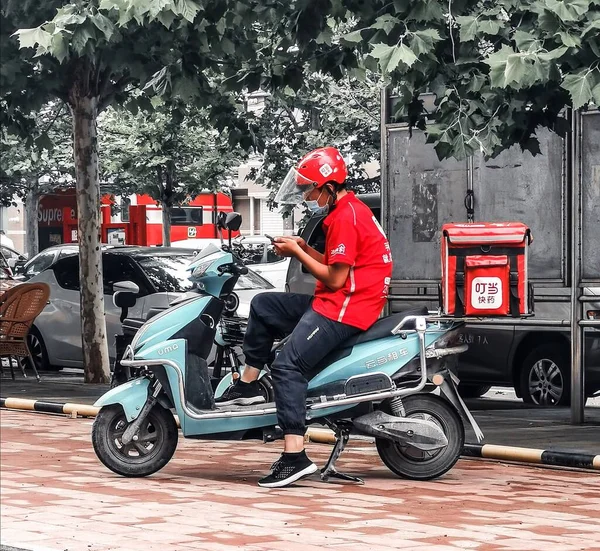 a man in a red jacket and a black shirt and a motorcycle helmet on the background of the city