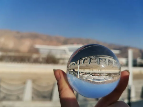 hand holding a glass ball on a background of blue sky