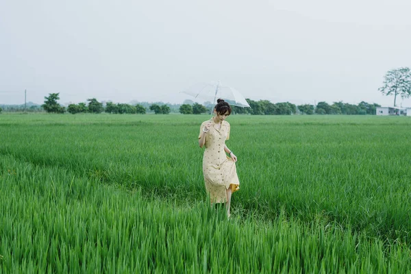 young woman in a green dress with a bag of rice in the field