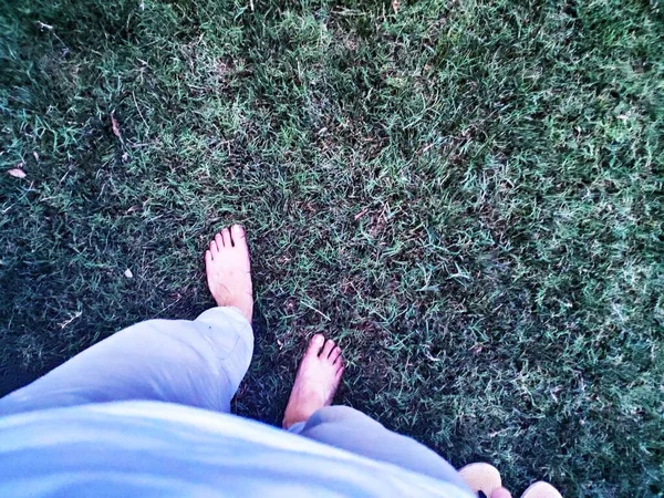 feet of a woman lying on the grass and looking at the camera