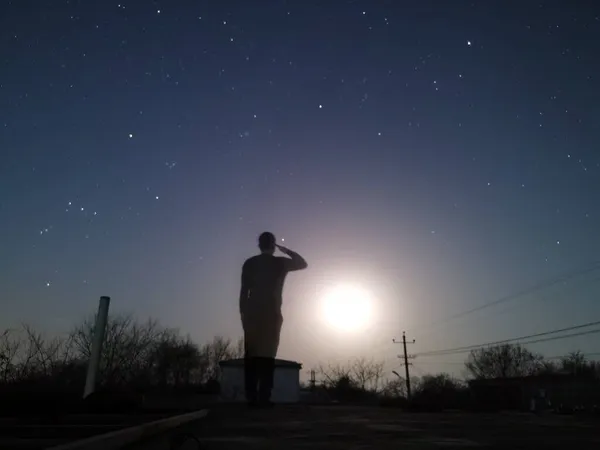 silhouette of a man with a backpack on the background of the night sky