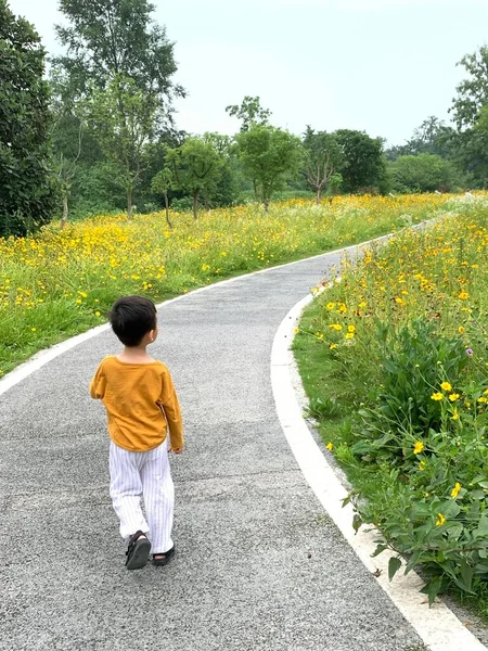 a boy in a yellow t-shirt and a white dress on a road in the countryside