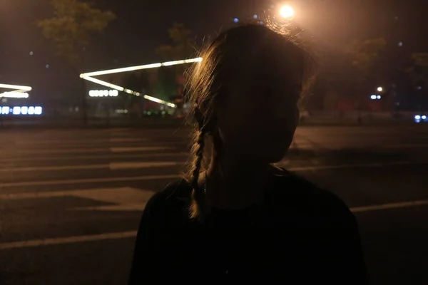 young woman with long hair in a black dress with a lantern on the street