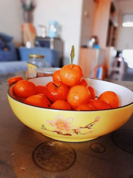 fresh orange and red oranges in a bowl on a wooden table