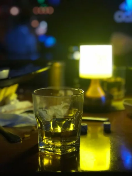 a glass of whiskey with a candle in a restaurant