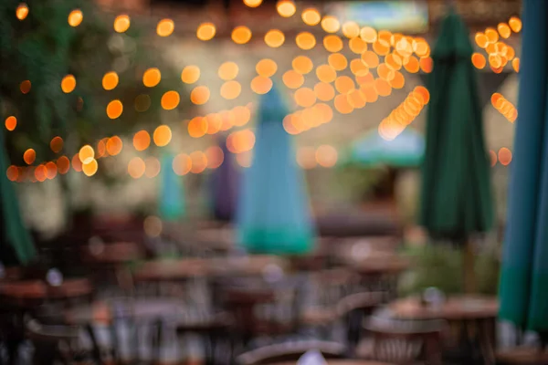 patio lights festive atmosphere in outdoor restaurant space with tables and chairs furniture objects ready for celebration event, no people