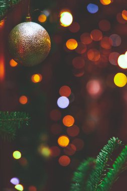 Dallarında top oyuncağı olan Noel ağacı dikey yumuşak odak resmi ve bulanık atmosfer ışıkları arka planda