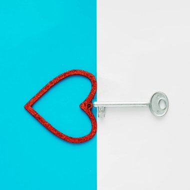 Gümüş bir anahtar mavi ve beyaz arka planda parlak kırmızı bir kalbi açar.