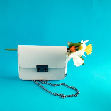 Mavi arka planda güzel bir buket çiçeğin çıktığı bir kadın çantası.