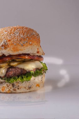 Eritilmiş peynirli hamburger, kızarmış pastırma, mayonez, marul, domates ve patates kızartması.