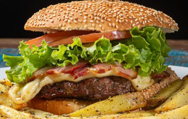 Eritilmiş peynirli hamburger, kızarmış pastırma, mayonez, marul, domates ve patates kızartması..
