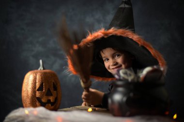 Cadılar Bayramı ortamında büyücü gibi giyinmiş küçük bir çocuk.