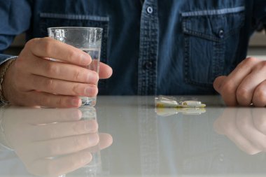 Beyaz bir adam evde migreni için ilaç alıyor.
