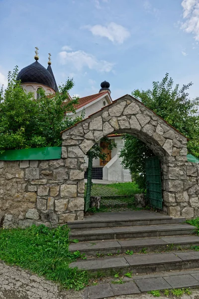 Ortodoks kilisesine basamaklı taş kemer girişi. Mavi gökyüzüne karşı haçlı çatılar ve kubbeler. Rusya, yaz zamanı..