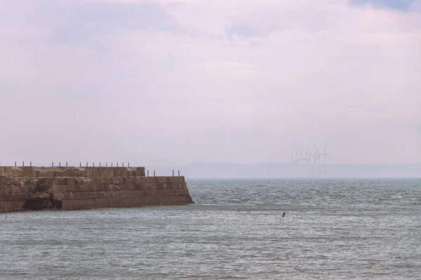 Jetée brise-lames de Heugh par temps orageux et nuageux avec parc éolien derrière — Photo