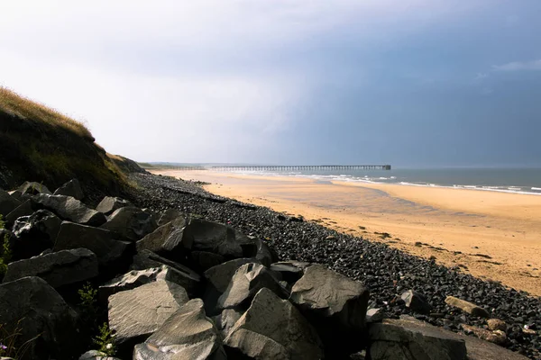 Black rocks and beach sand on stormy day at Hartlepool Headland, UK — Photo