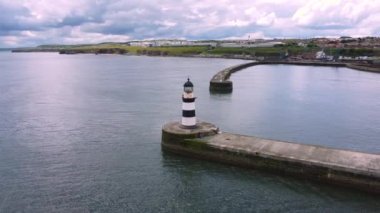 4k, Durham, İngiltere 'de Seaham deniz feneri ve rıhtımının üzerinde daireler çizen insansız hava aracı atışı.