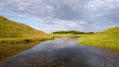 Reflections in water and reeds in Northumberlandia, a huge land sculpture in the shape of a reclining female figure, which was completed in 2012, near Cramlington, Northumberland, northern England.