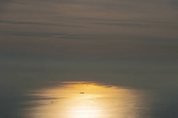 Vast Sea Dwarfs Silhouetted Boat Streaky Clouds Bright Orange Reflected — Foto Stock