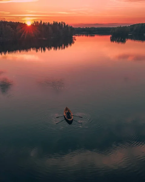Mężczyzna wiosłujący na spokojnym jeziorze o zachodzie słońca — Zdjęcie stockowe