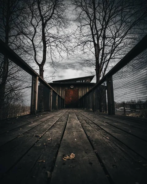 Nízký úhel pohledu na dřevěný most vedoucí k záhadným dveřím. Dramatický kino jako střih. — Stock fotografie