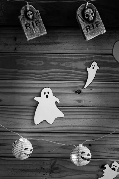 Halloween decorations, pumpkins, pumpkins, graves and ghosts on a black and white wooden background