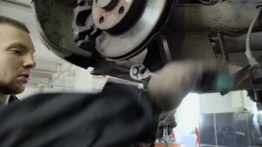 Mechanic tighten the bolt of the car with a tool