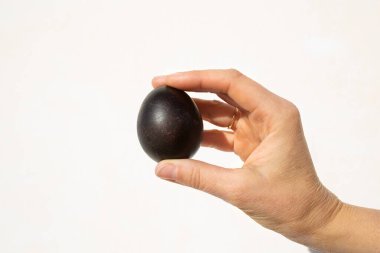photo of a black egg in hand on a white background. Easter theme