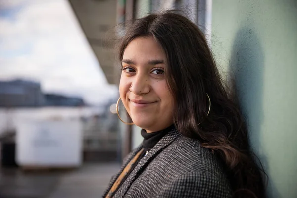 Gülümseyen genç bir kızın portresi. Mutlu ve sakin genç dişi sırtını duvara dayıyor. Güzel Kuzey Afrikalı kız. Mutlu gençlik kavramı