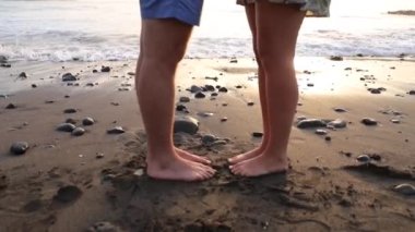 Gün batımında kumsalda birbirine aşık bir çiftin ayaklarına yakın çekim. Romantik ve birliktelik kavramı