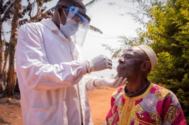 Bir doktor yaşlı bir Afrikalı hastaya koronavirüs testi uygular. Afrika 'da Covid-19 testi