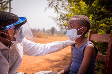 Afrikalı doktor serolojik teste girmek üzere olan küçük bir çocuğu ziyaret etmekle meşgul..