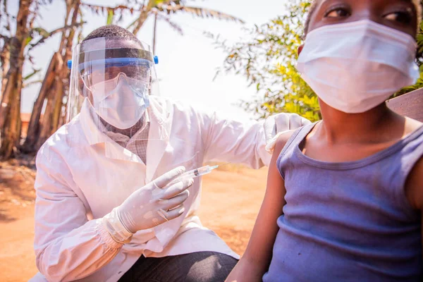 Afrikalı bir çocuk köydeki bir açık hava merkezinde koronavirüse karşı aşı oluyor..