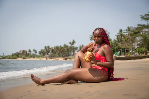 Attractive Single Black Woman Sitting Sand Beach Sipping Coco Milk — Stockfoto