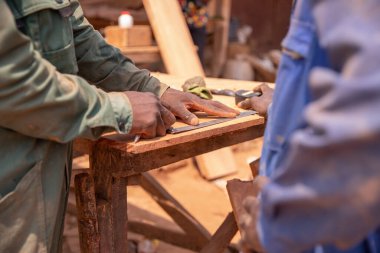 İki marangozun elleri, çalışırken tahta bir tahtanın üzerinde ölçüm yaparken.