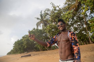 Çekici bir adam Afrika 'da tropik bir plajda selfie çekiyor.