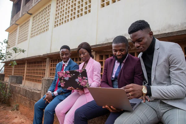 Four young adults work using their laptops and discussing job issues in Africa