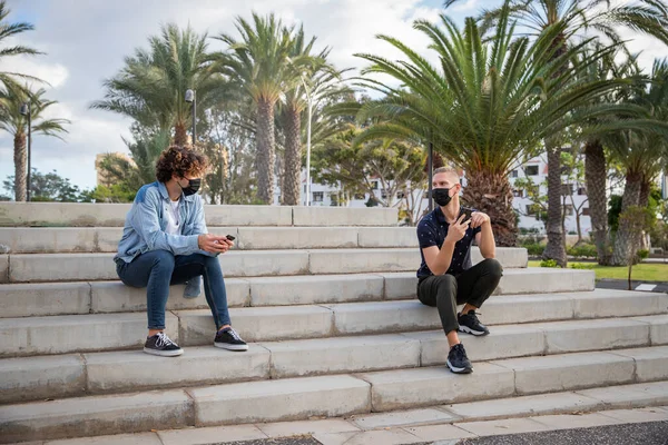 Two Boys Sitting Stairs Use Smartphones While Wearing Surgical Masks — Stok fotoğraf