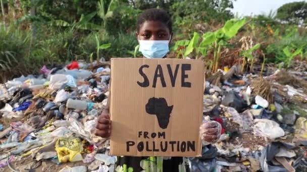 一个女孩在一个非法露天垃圾填埋场前举着写着 拯救非洲不受污染 的标语 — 图库视频影像
