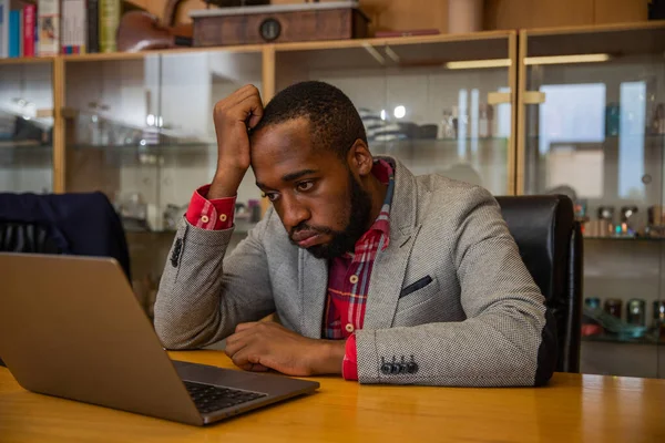 A businessman is sad and angry while he is in the office looking at his laptop screen.