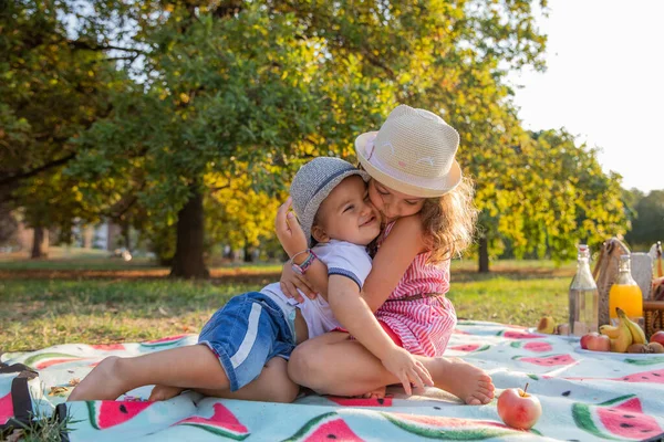 Two siblings hug each other during a picnic in a public park, family love